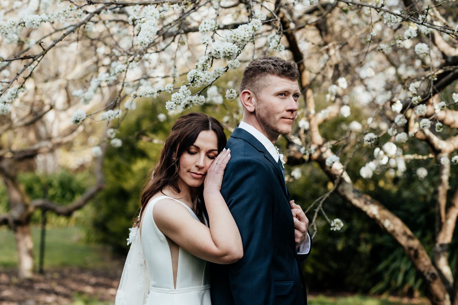 A bride and groom under blooming cherry blossom trees in spring during their romantic elopement in Martinborough Wairarapa by August & Vine