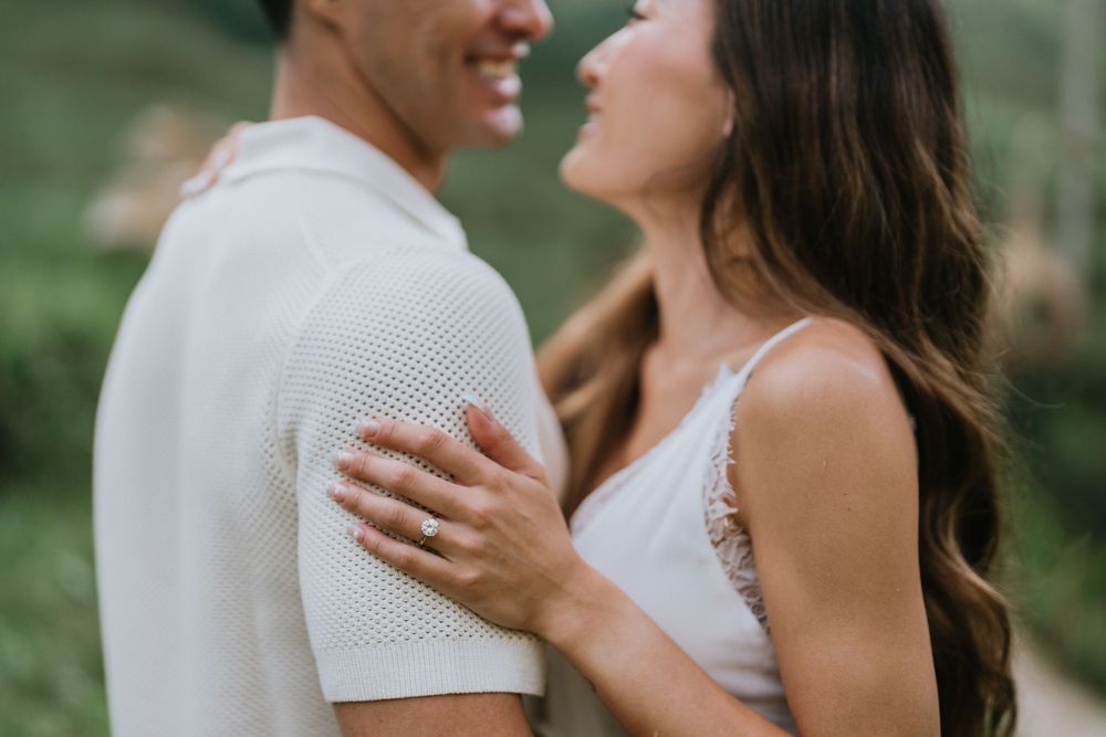 Close-up of a couple sharing an intimate moment in white outfits against a tropical backdrop.