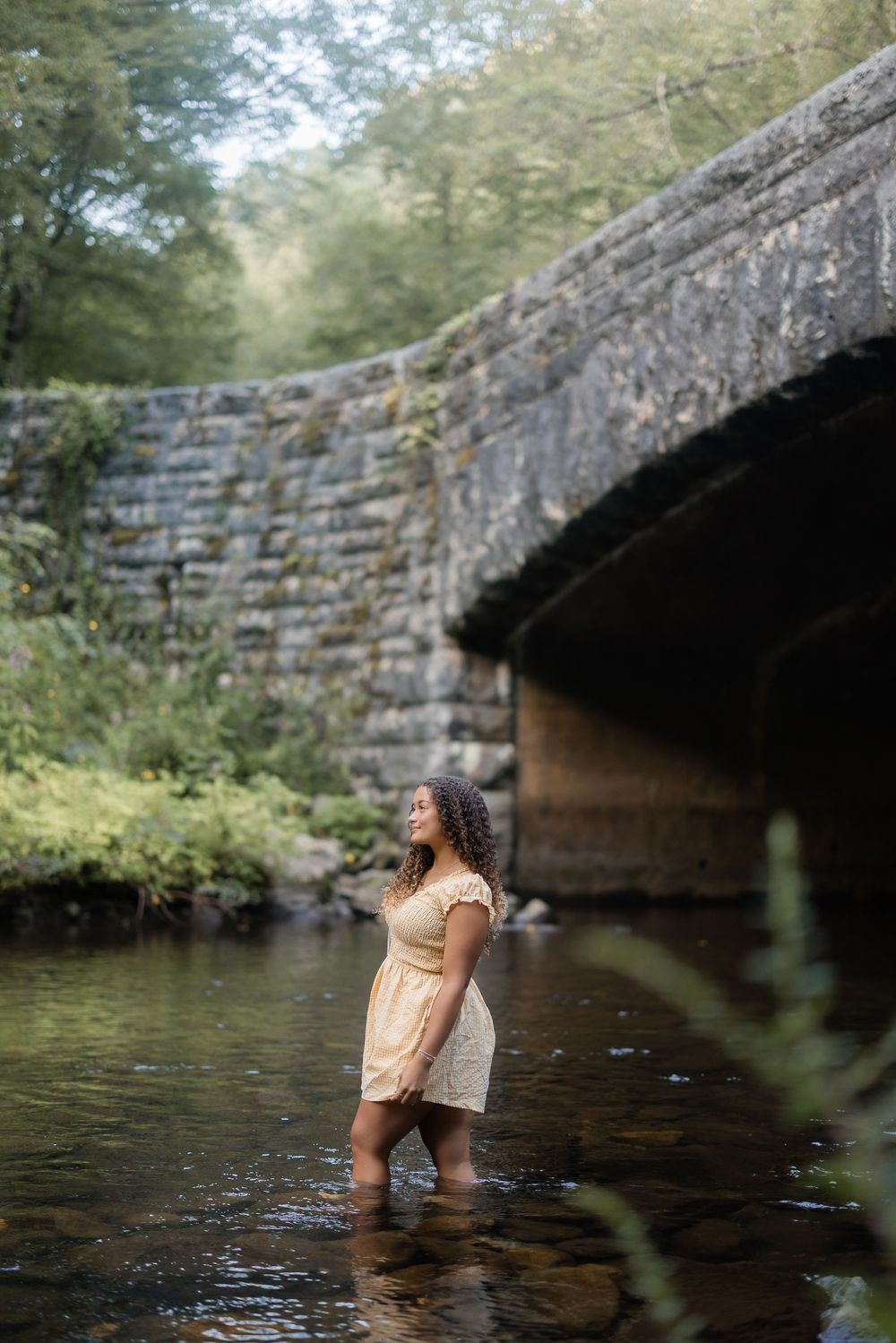 A sequence of photos showing someone exploring a stone bridge arch over calm water surrounded by greenery.