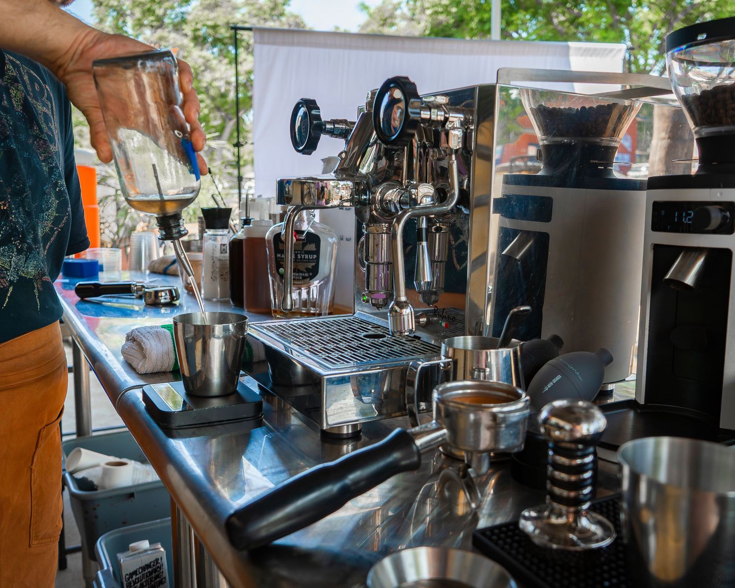 Stainless steel coffee bar setup with espresso machines, grinders, and barista tools.