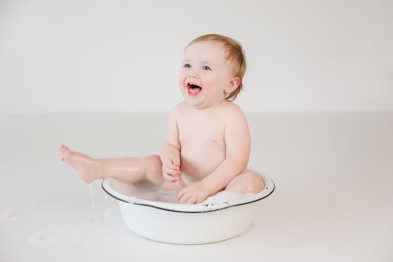 A sequence of photos showing a baby sitting on the floor during a birthday cake smash photoshoot.