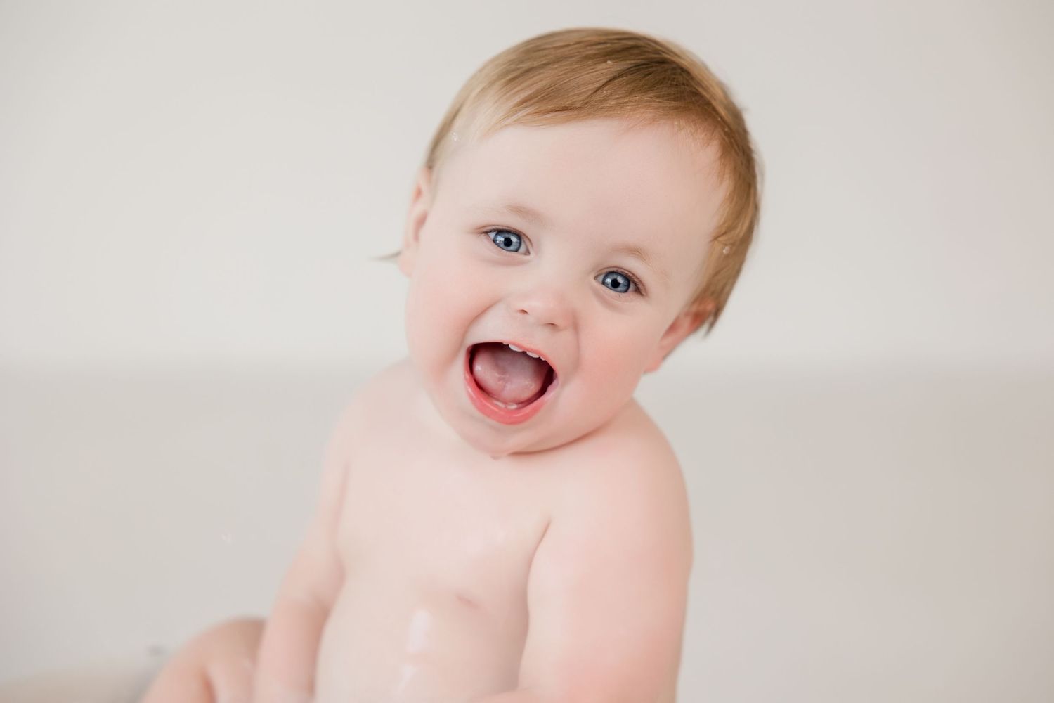 Cheerful baby with bright smile against plain light background.