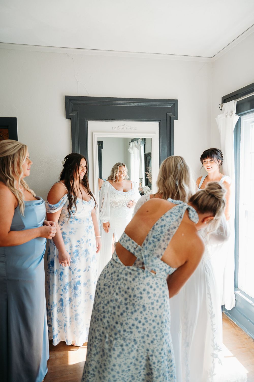 bridesmaids helping bride into dress at Sister Hill venue in Manchester Iowa by midwest wedding photographer Elisa Tonne