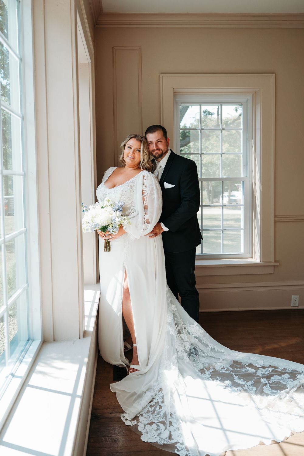 bride & groom posing in front of big window in Sister Hill venue Manchester Iowa by midwest wedding photographer Elisa Tonne