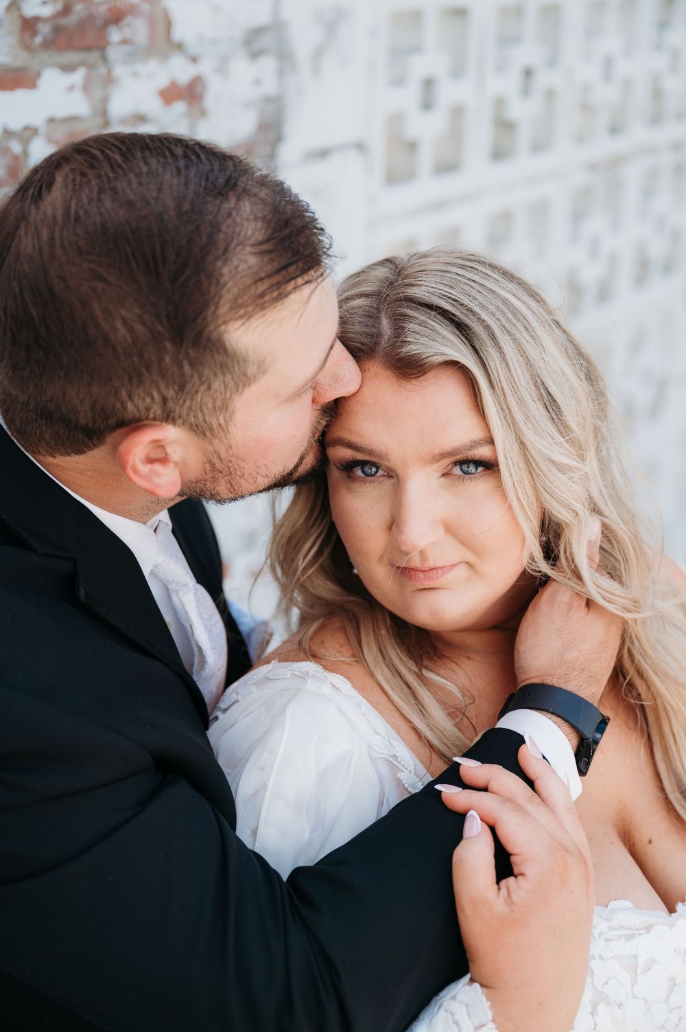 Groom kissing brides forehead as she gazes into lens outside Sister Hill wedding venue Manchester Iowa by midwest wedding photographer Elisa