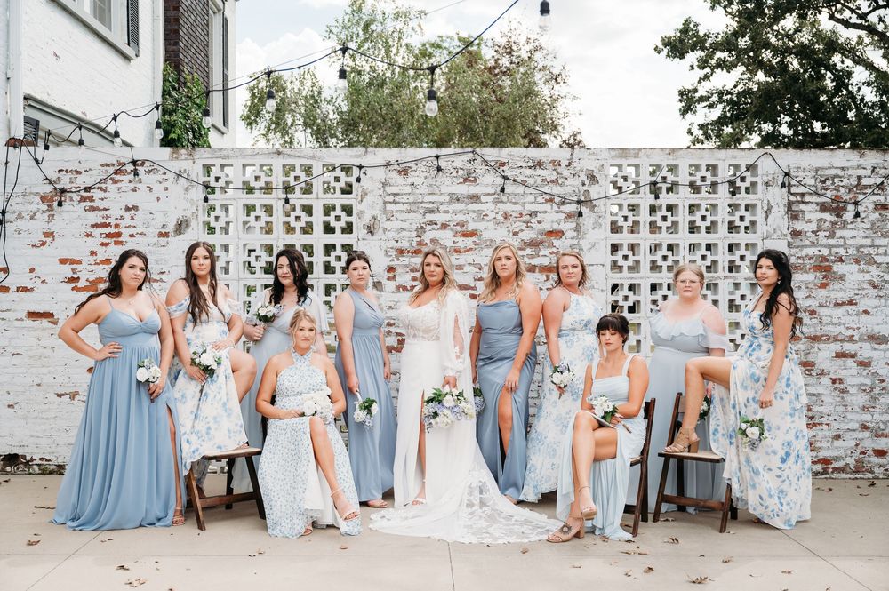 bride & bridesmaids outside brick wall ceremony area at Sister Hill venue Manchester Iowa by midwest wedding photographer