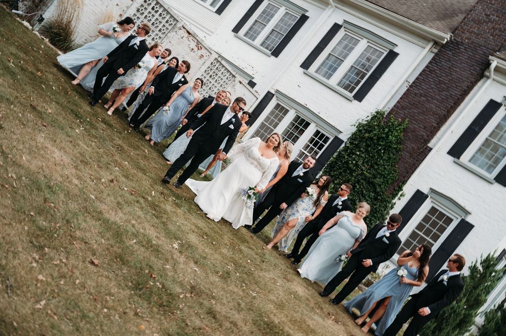 sideways image of bridal party walking towards camera outside Sister Hill venue Manchester Iowa by midwest wedding photographer