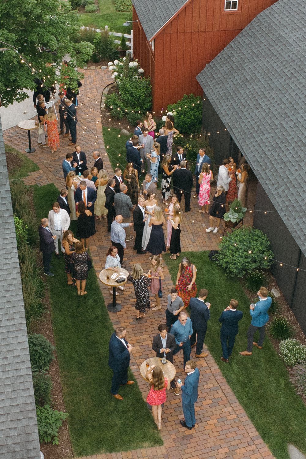Wedding guests mingling outside a rustic red barn during an outdoor reception.