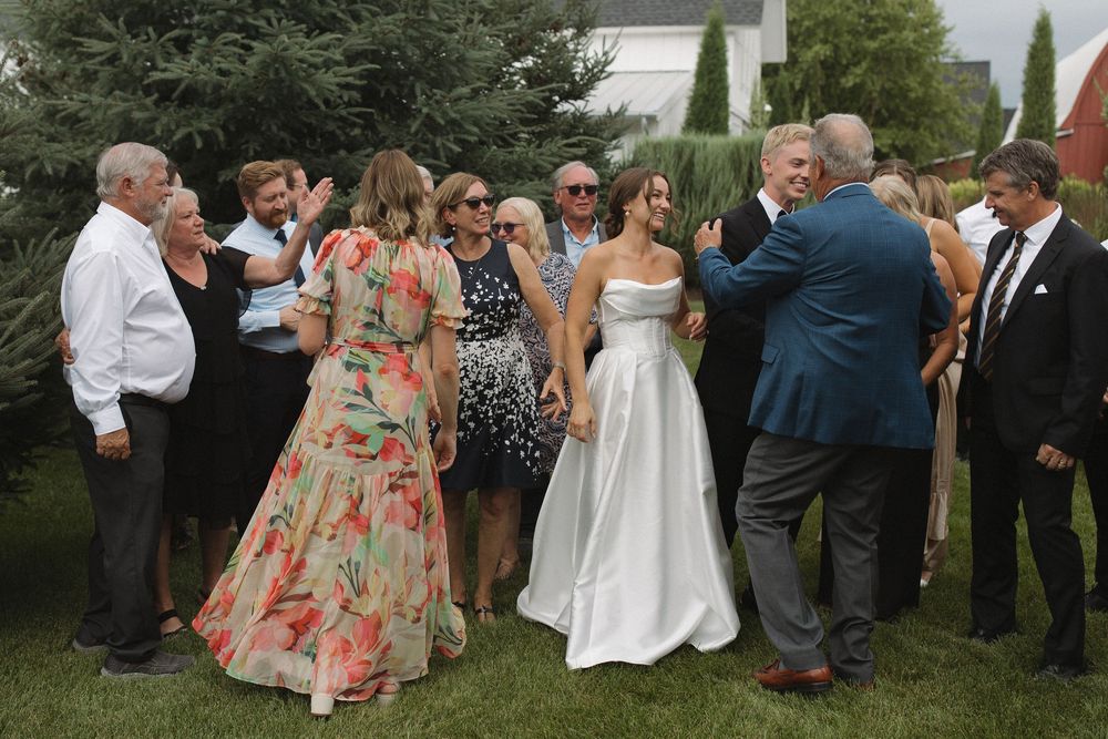 Wedding guests in floral dresses gather outdoors during a celebration.