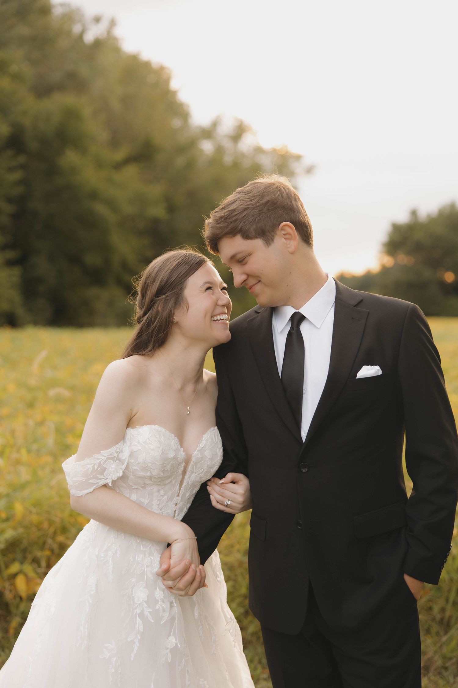 A romantic wedding couple shares an intimate moment in a wildflower field at sunset.