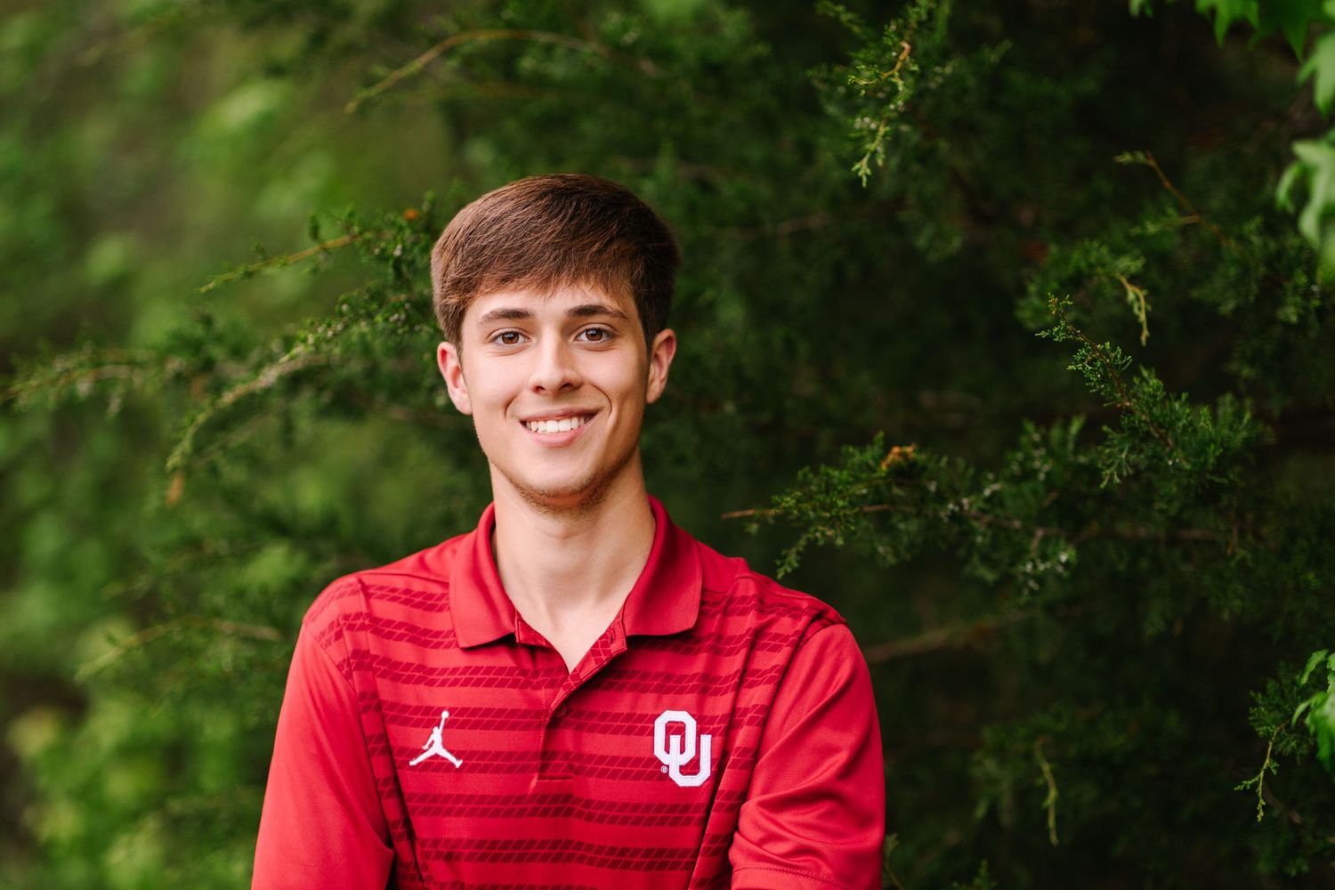 A series of sports portrait photos in an outdoor setting with green foliage and red uniforms.