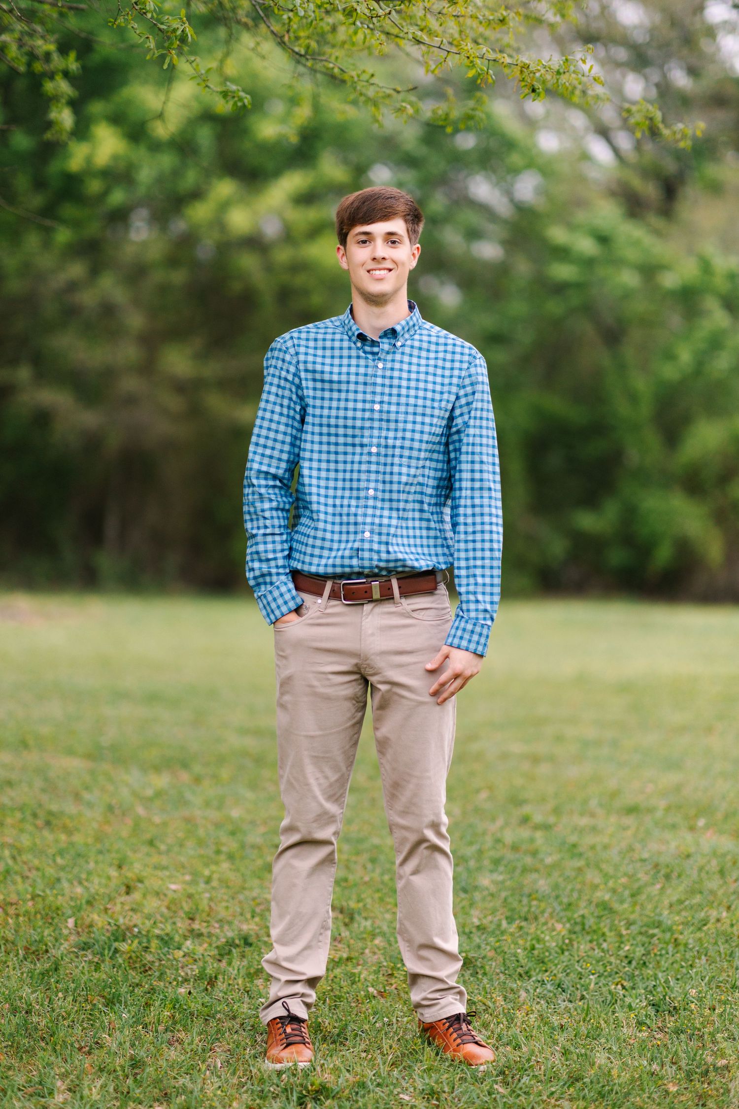 Multiple casual poses of someone wearing khaki pants and blue gingham shirt standing on grass with trees in background.