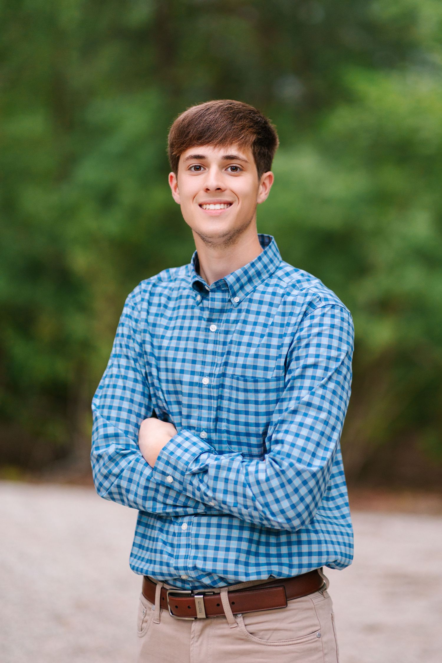 Portrait of someone wearing a blue and white checkered button-up shirt against a blurred green background.