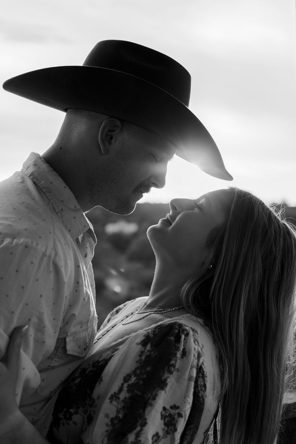 Black and White Cowboy hat styled engagement portraits with rustic hill country backdrop in Dripping Springs, Texas.