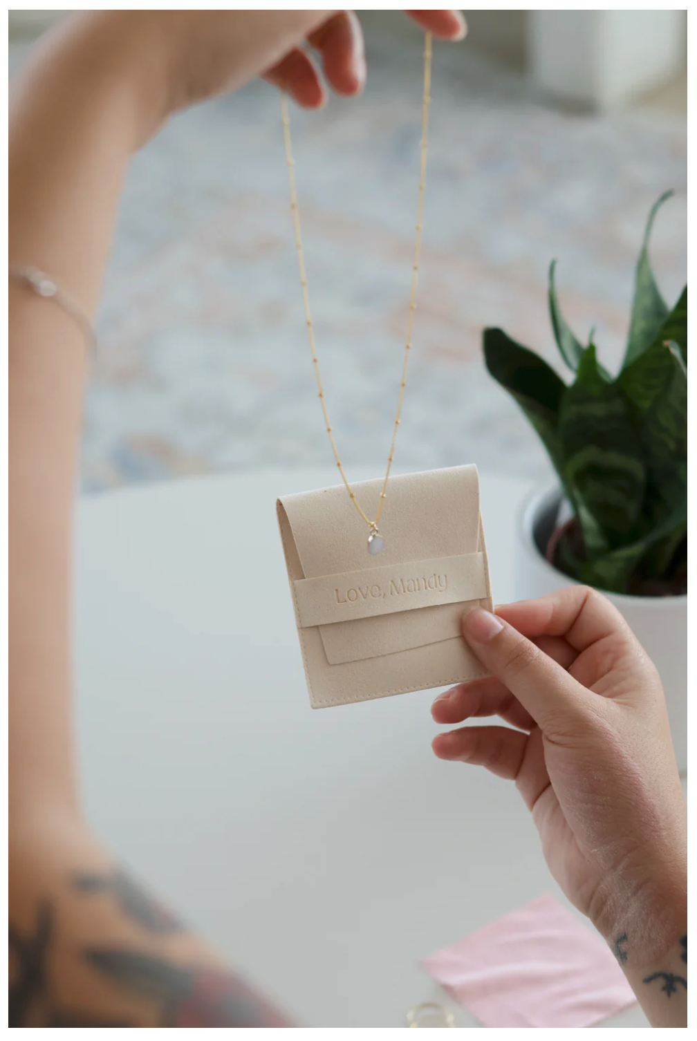 Hand holding a beige retail shopping bag tag in natural daylight against a white background.