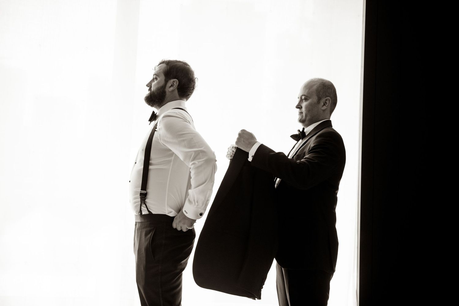 Two people in dark suits sharing emotional embrace.