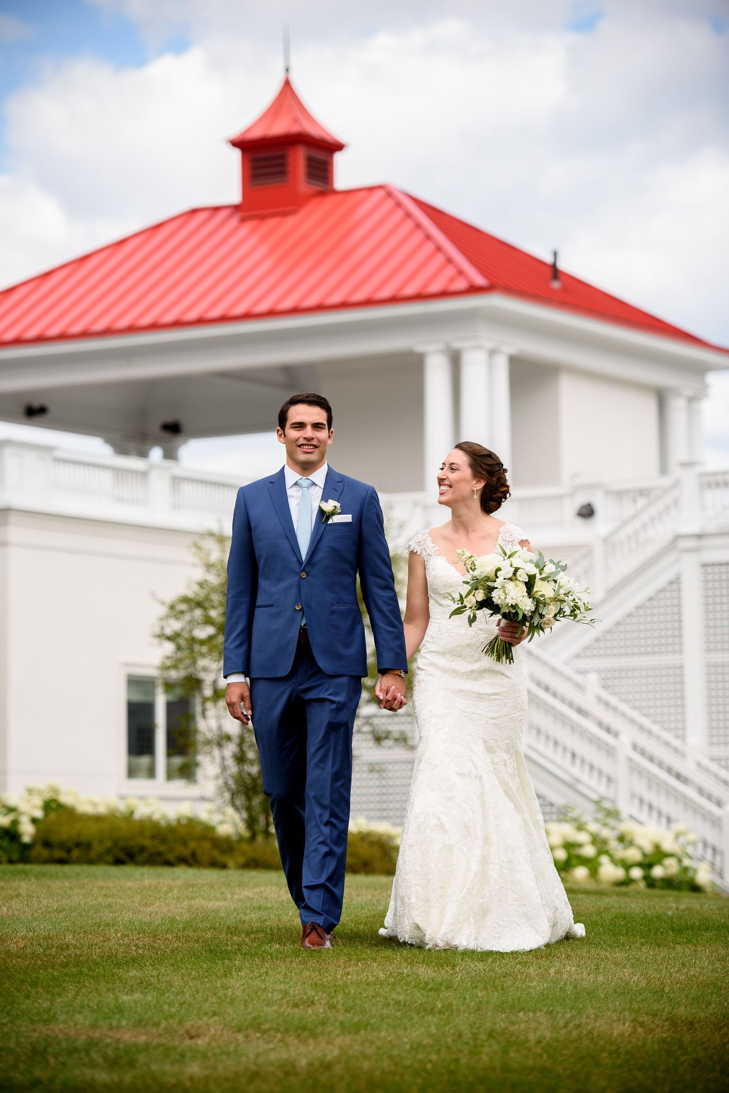 Wedding couple walking on the manicured lawn of the South Veranda at the Omni Mt. Washington Hotel & Resort on a beautiful sunny day.