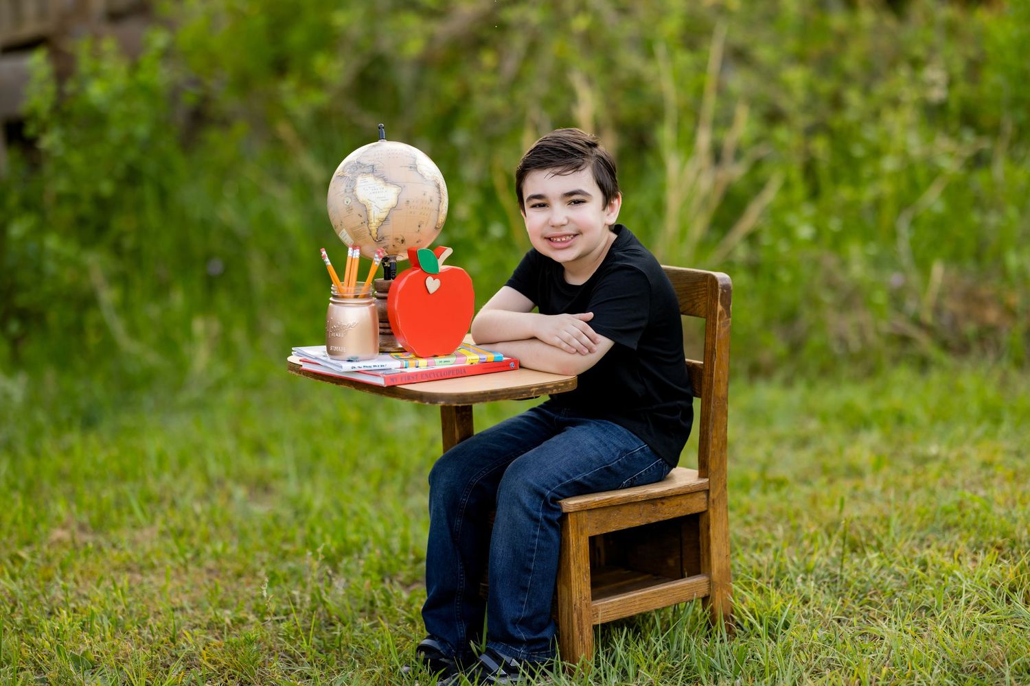 A group of wooden chairs arranged on a grassy lawn with orange accents at a social gathering.