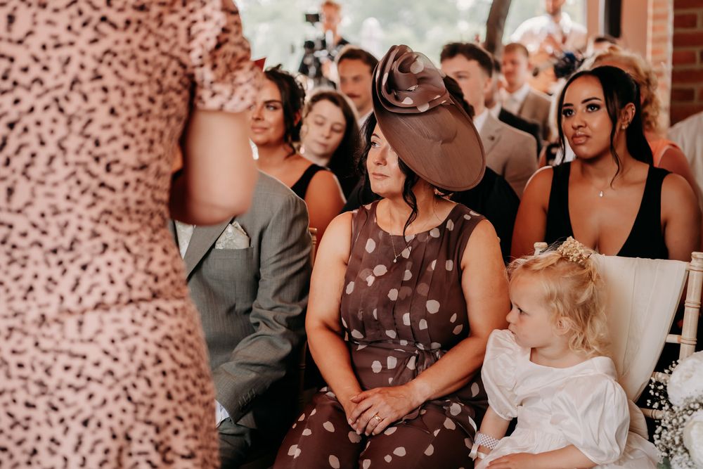 Wedding guests make emotional reactions during a special moment at an indoor venue.