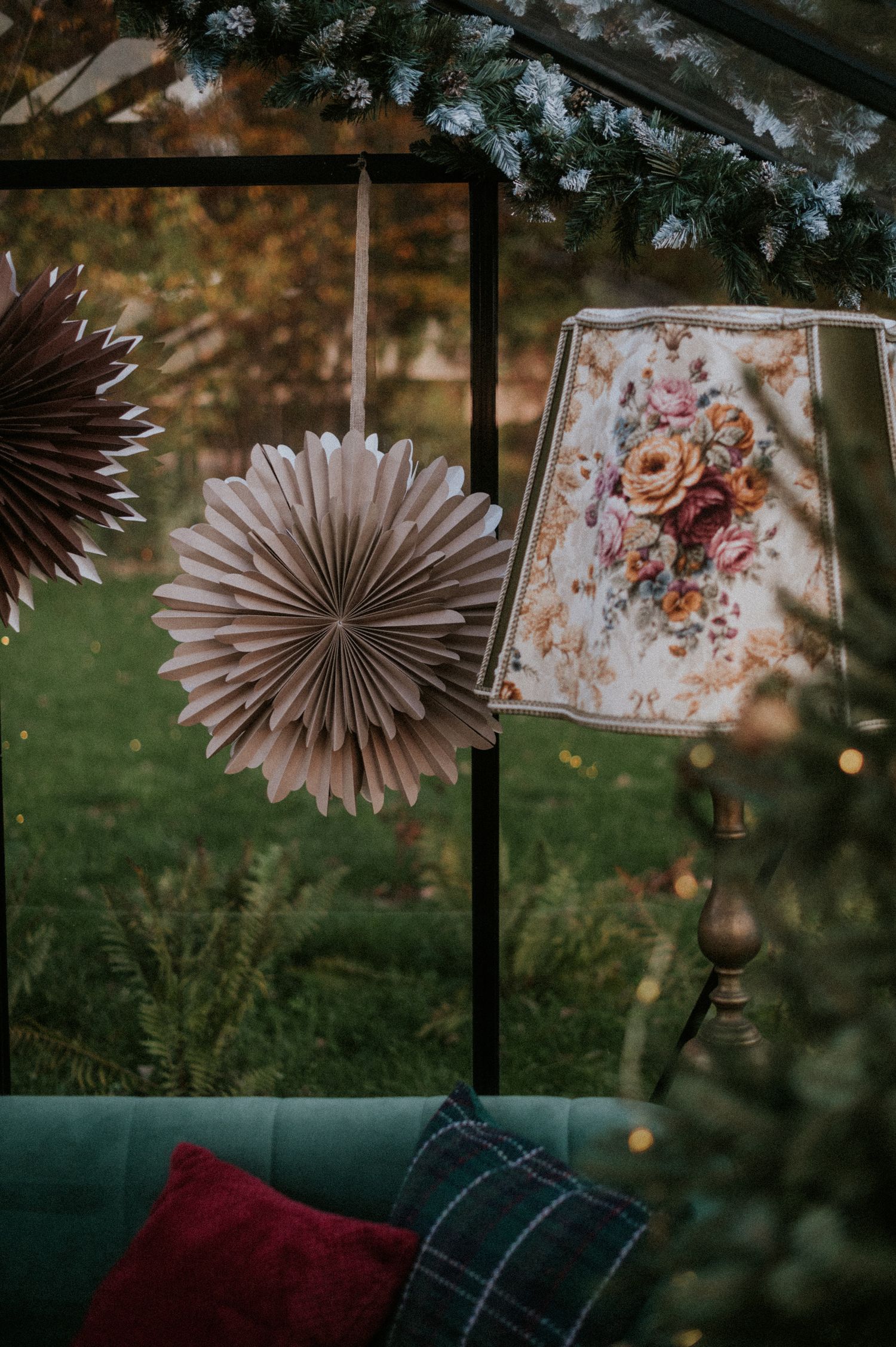 Paper fan decorations and floral artwork create a cozy outdoor seating area with plush cushions and string lights.