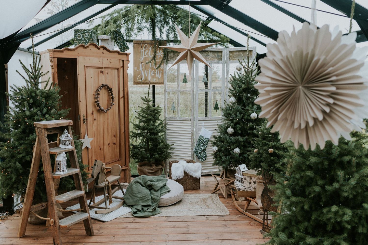 A festive Christmas scene with natural wood decorations, evergreen trees, and rustic decor in a cozy indoor space.