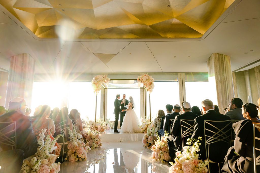 Reception venue decorated with dramatic red lighting and illuminated chandeliers during a celebration.