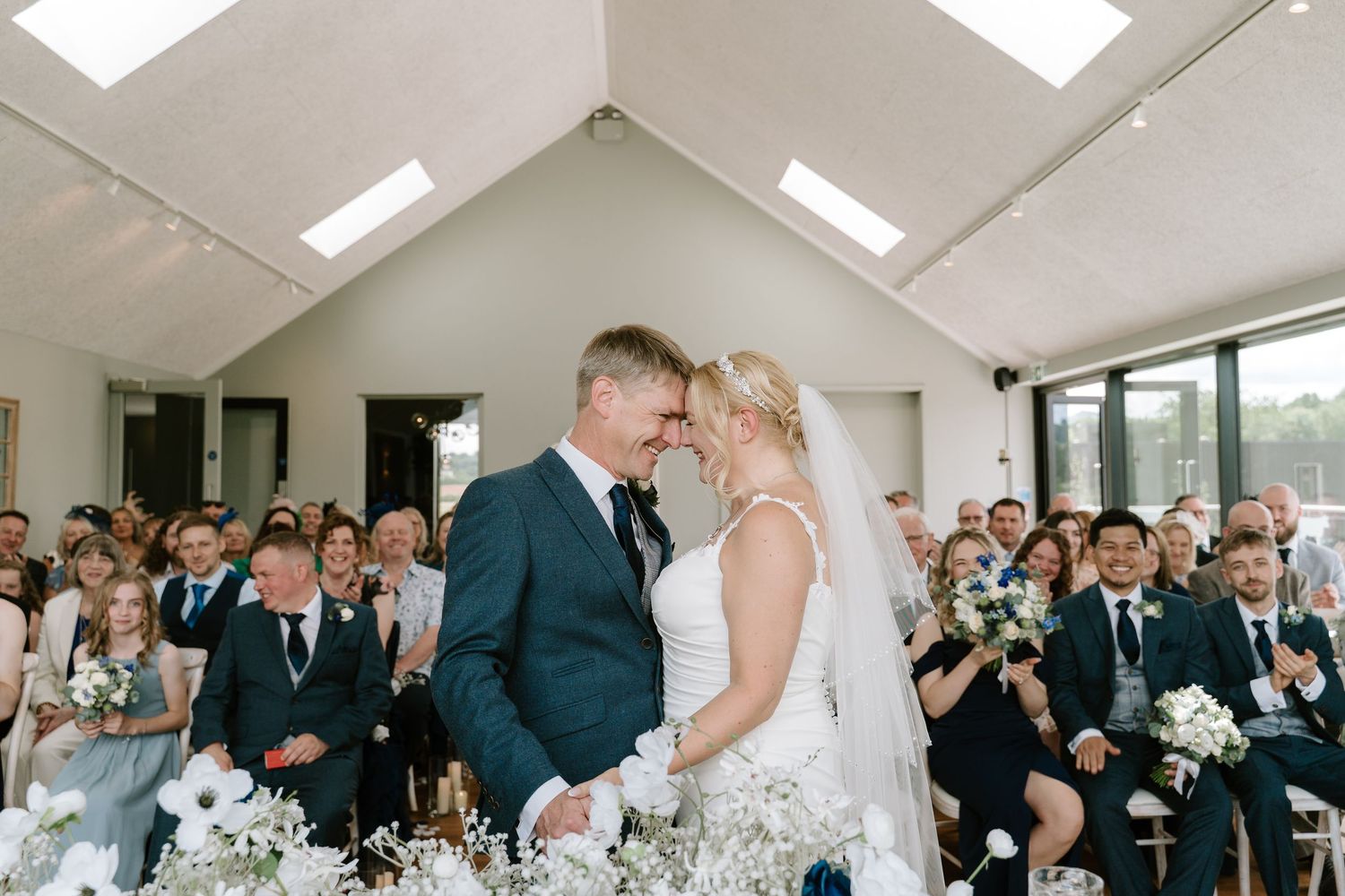 A series of candid wedding photos showing tender moments between a couple and their guests during a bright indoor ceremony.