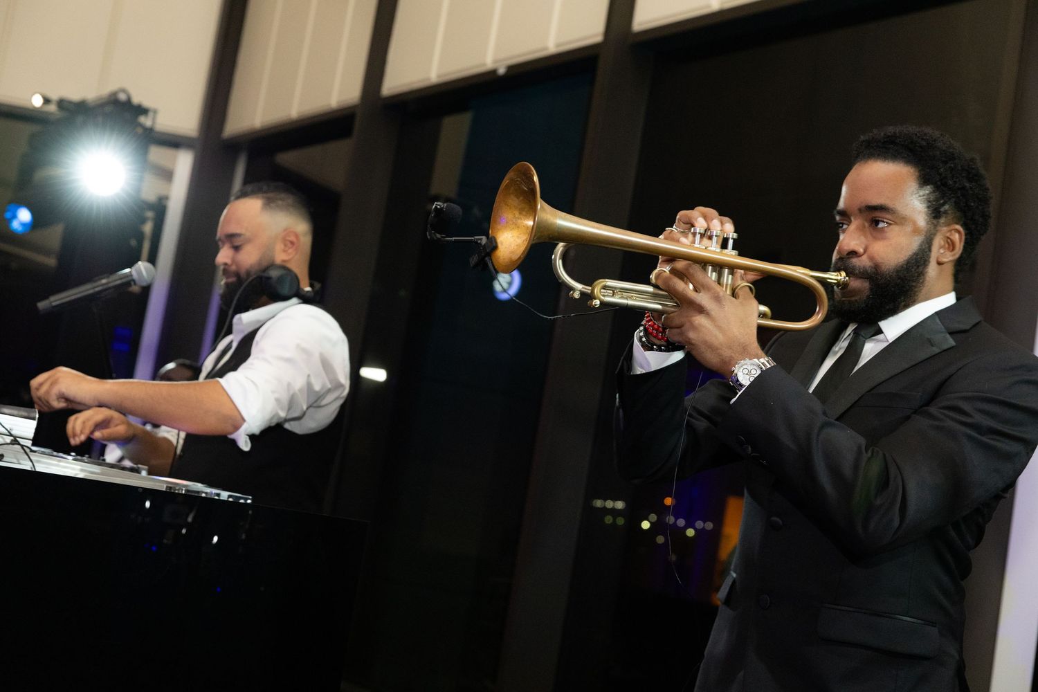 Trumpet player performs energetically at a dimly lit nightclub stage with blue lighting effects.