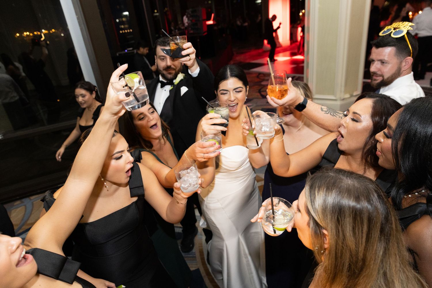 Wedding guests raise their glasses in a celebratory toast at an elegant reception party.