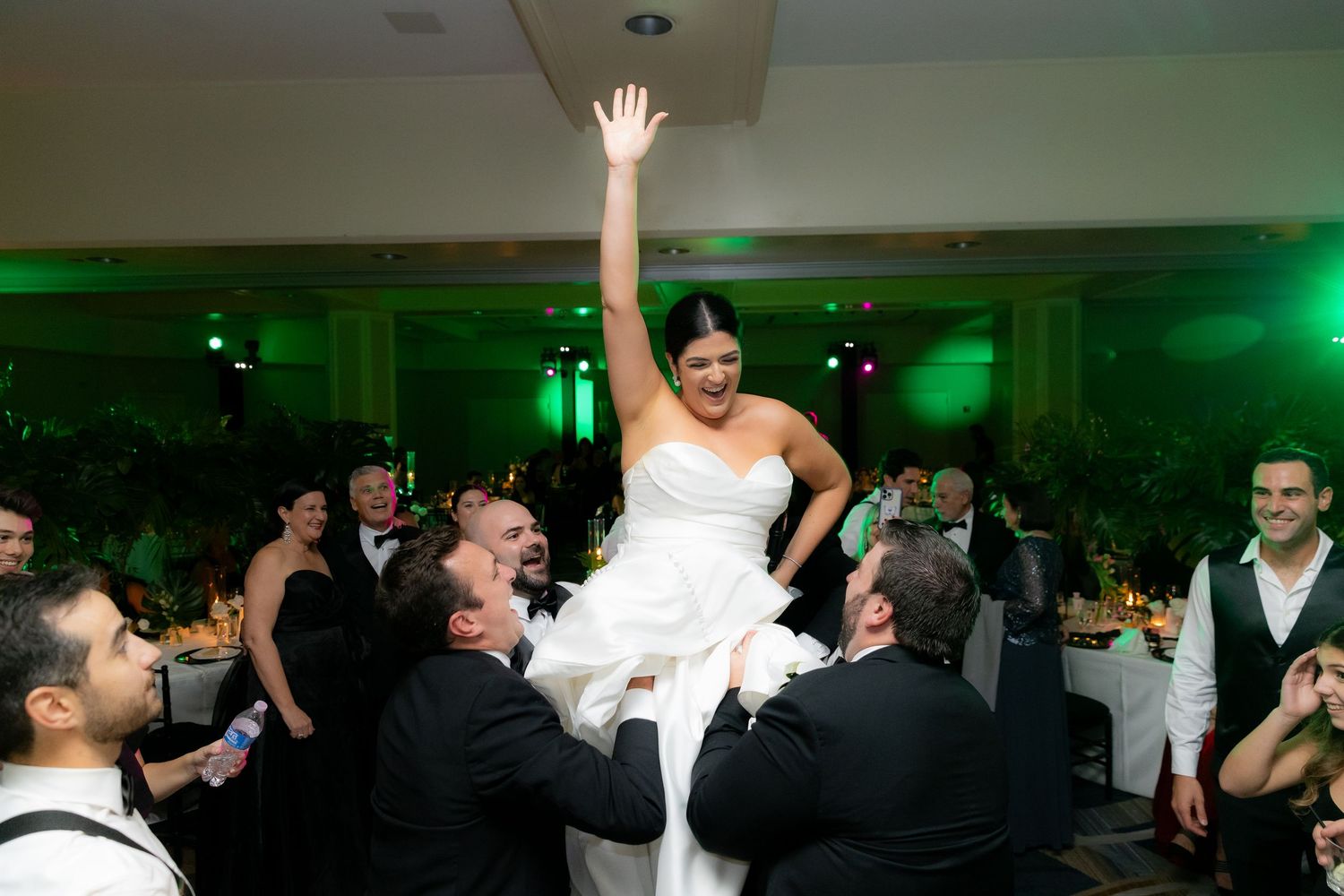 Lively wedding reception dance floor filled with guests enjoying music and dancing under ambient lighting.