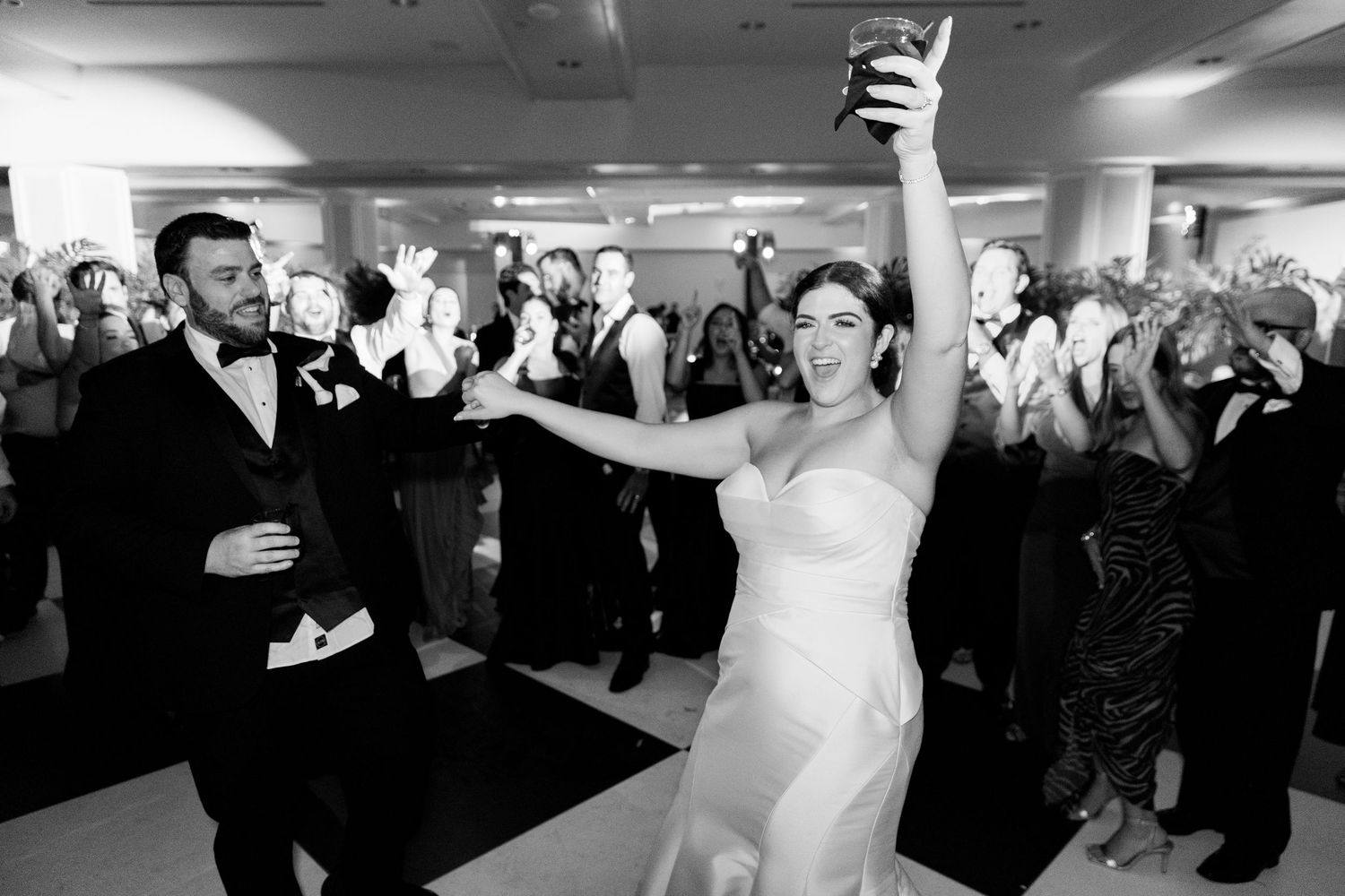 Wedding reception guests dance and celebrate together on a dance floor in a lively indoor venue.