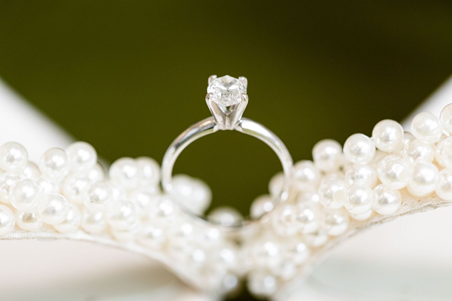 Close-up detail of delicate pearl beading and crystals on white fabric.