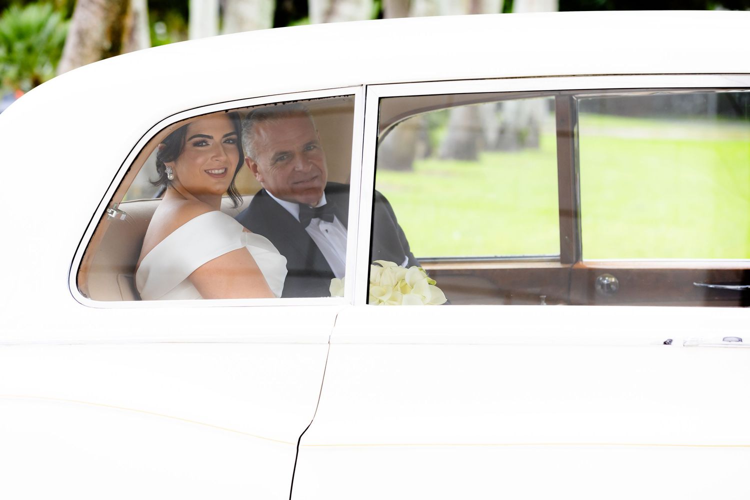 Newlyweds share an intimate moment in the back of a classic wedding car.