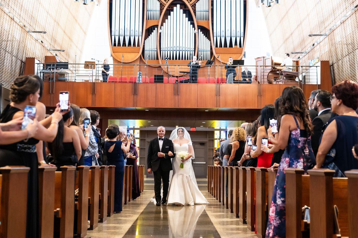 Wedding ceremony in a grand church with high vaulted ceilings and wooden pews.