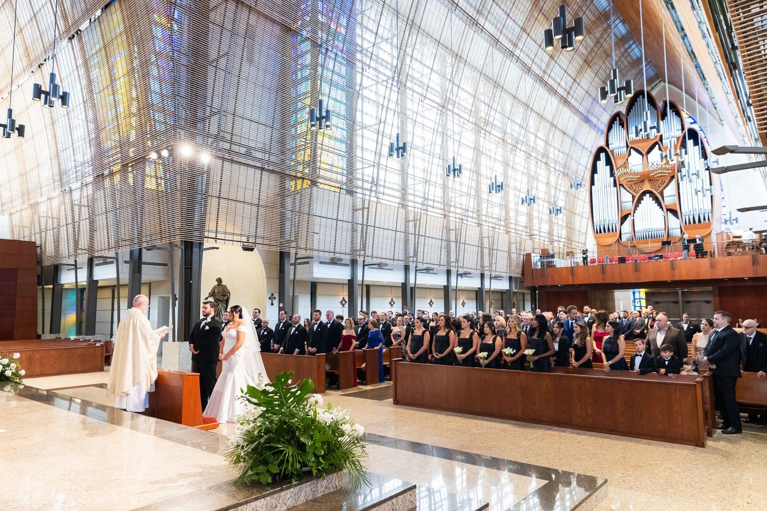 Elegant church interior with vaulted ceilings and hanging chandeliers during a wedding service.