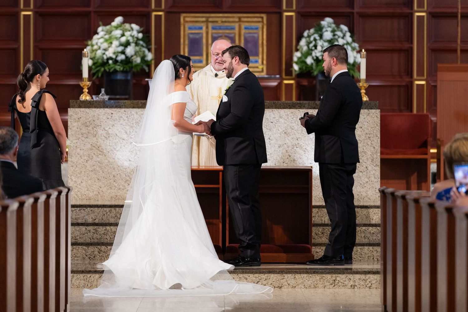 Wedding ceremony in progress at an ornate church altar with floral decorations.