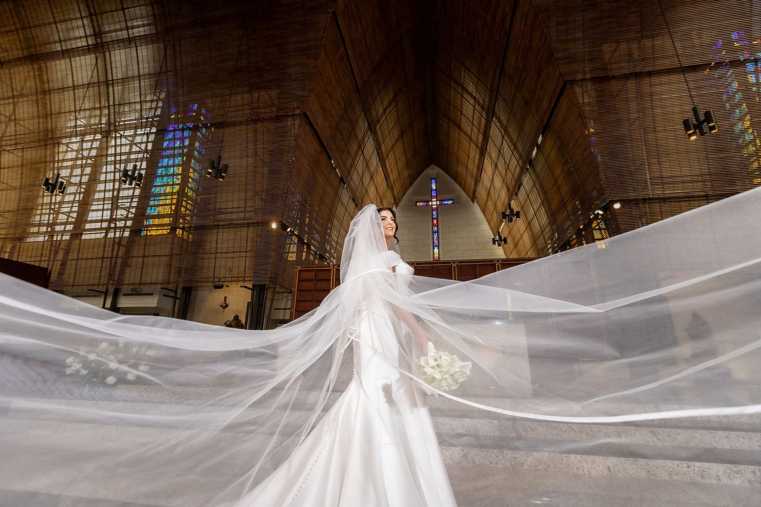 Dramatic cathedral photo with flowing wedding veil and gothic architecture.