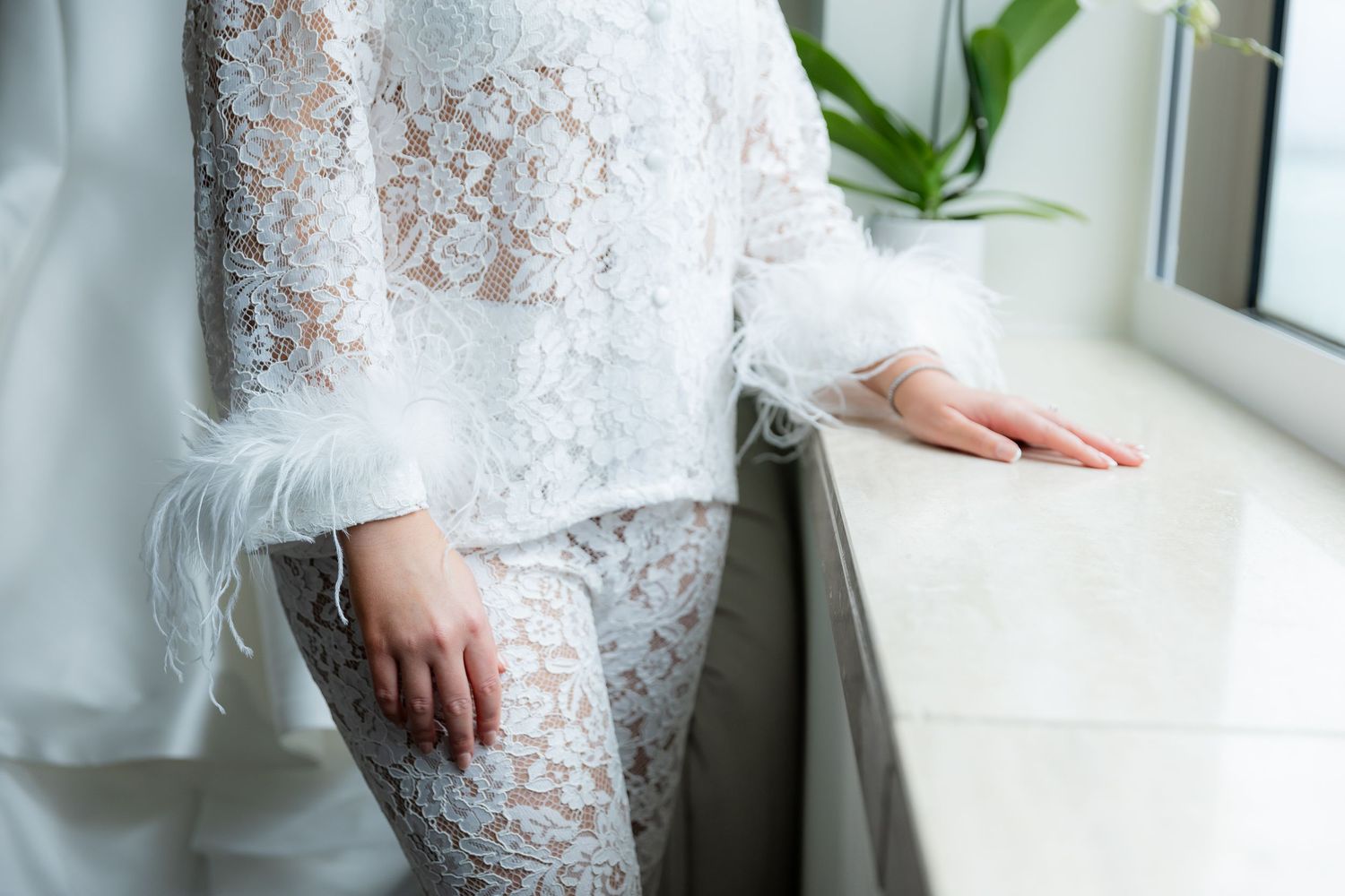 Close-up detail of delicate white lace wedding dress fabric and beading.