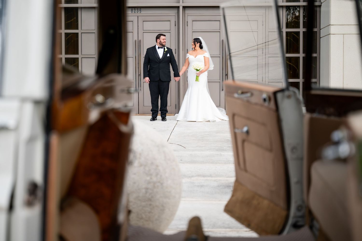 Elegant wedding couple poses in front of classic architectural doorways and columns.