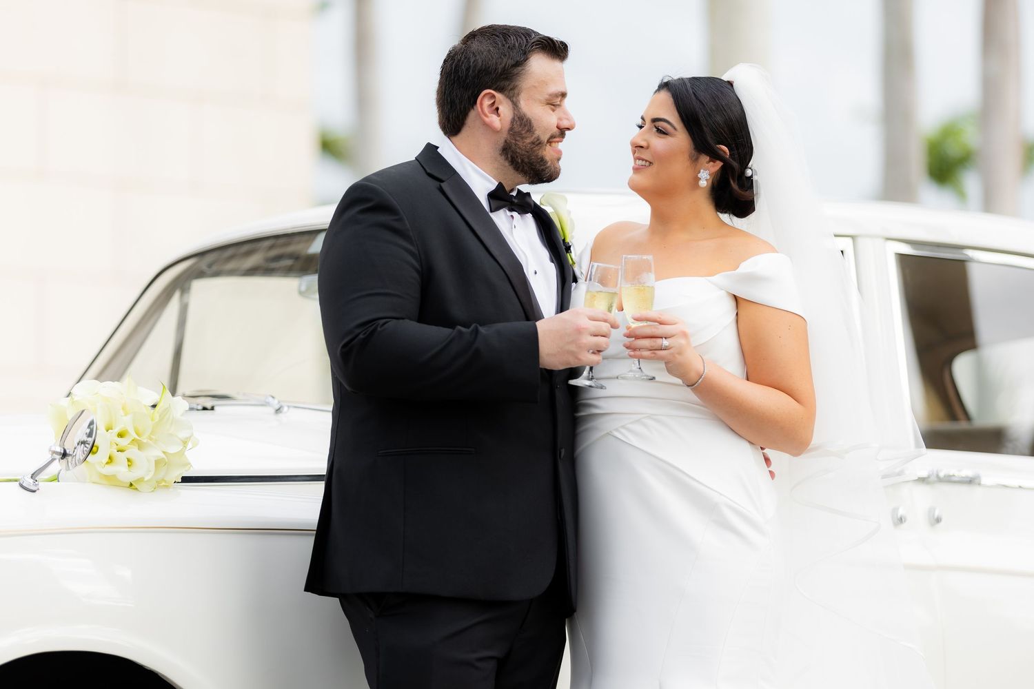 Wedding couple sharing champagne toast and laughing together outdoors.