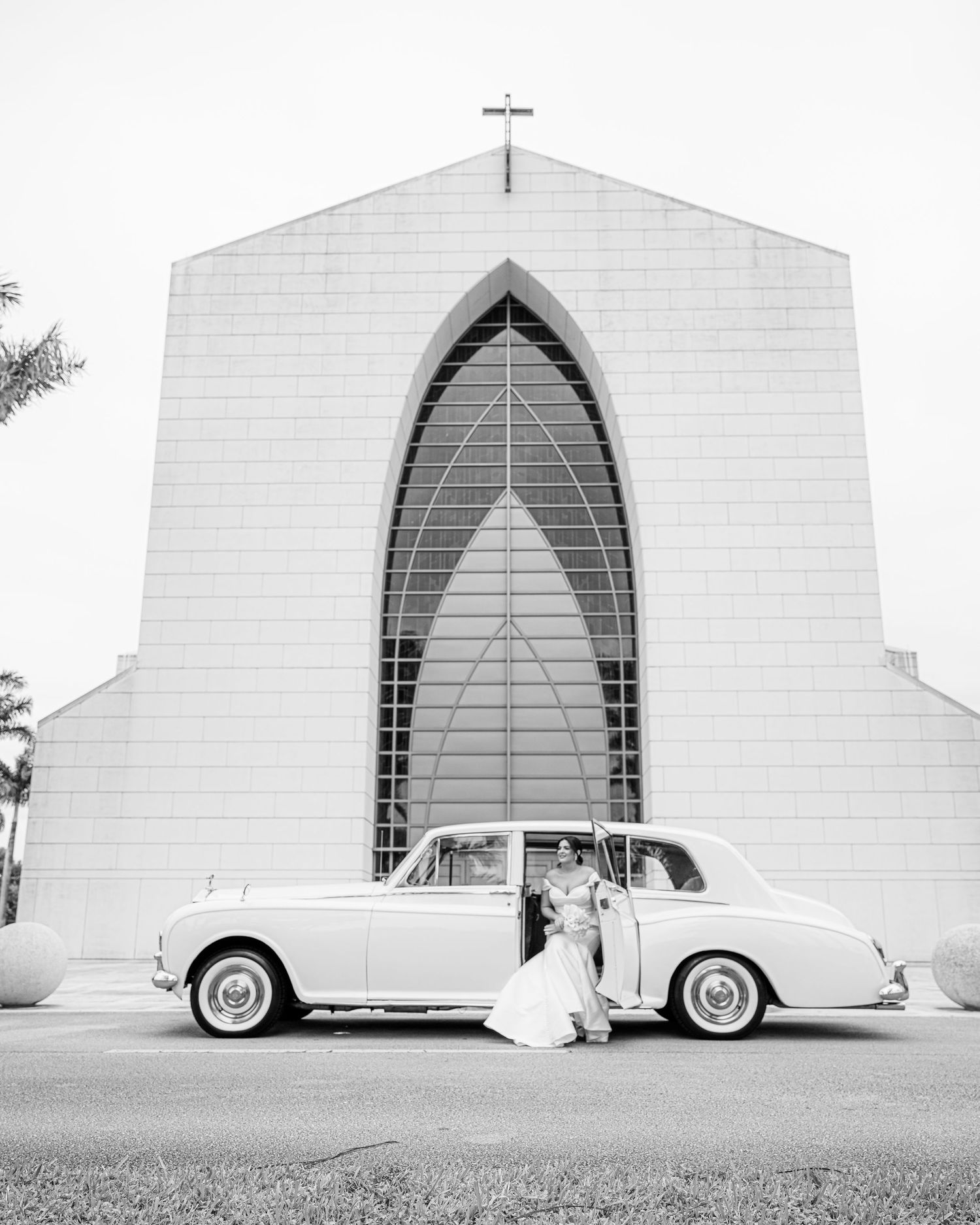 Five black and white photographs show a classic white car parked against a white architectural structure with arches.