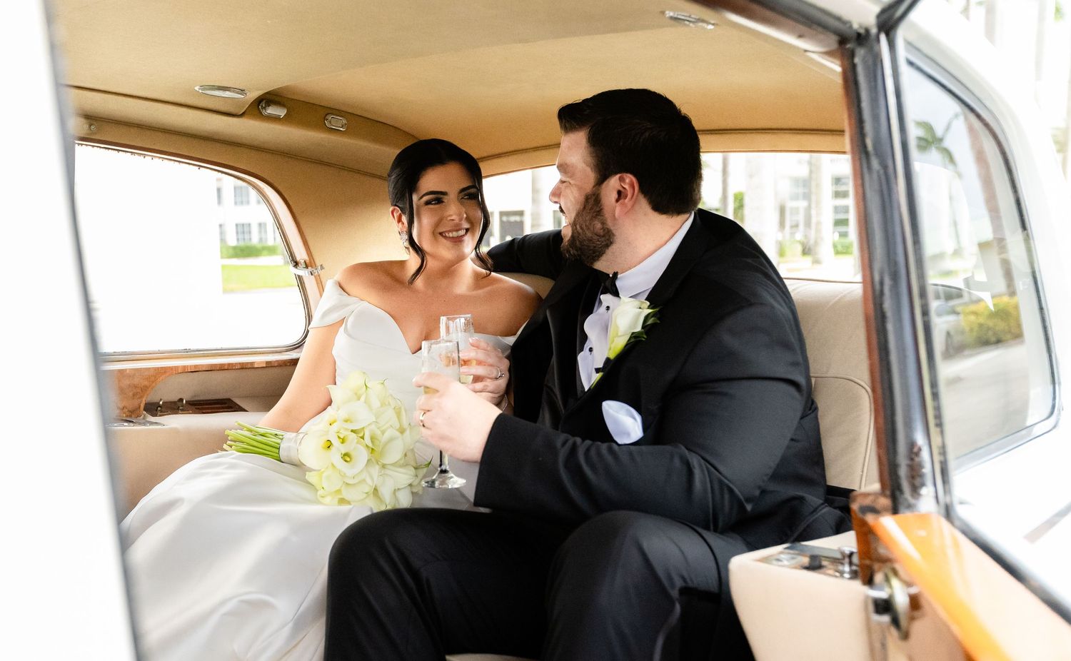 Newlyweds share intimate moments inside a vintage car during their wedding day.