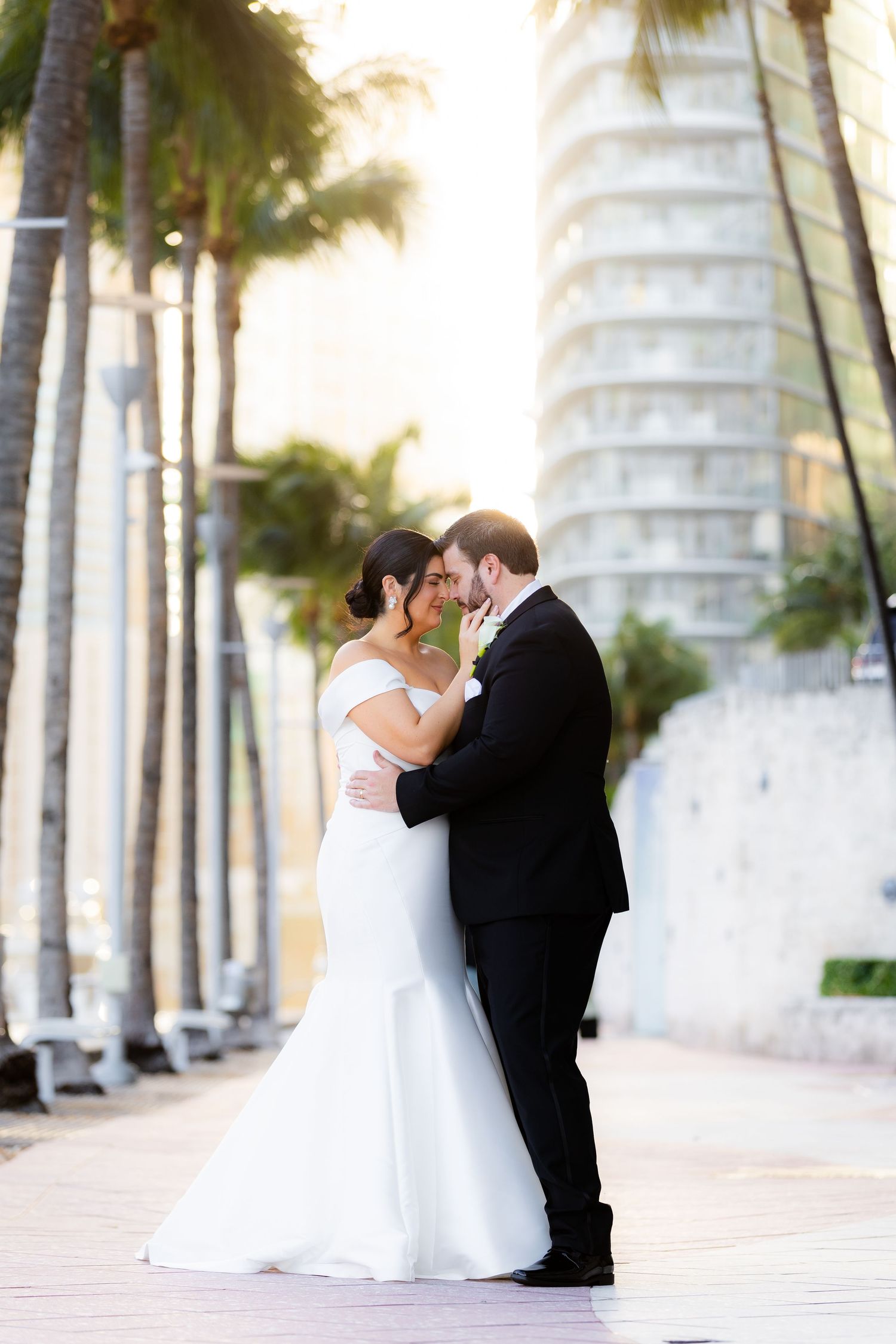 Palm trees create a romantic backdrop for wedding portraits along a sunlit path.