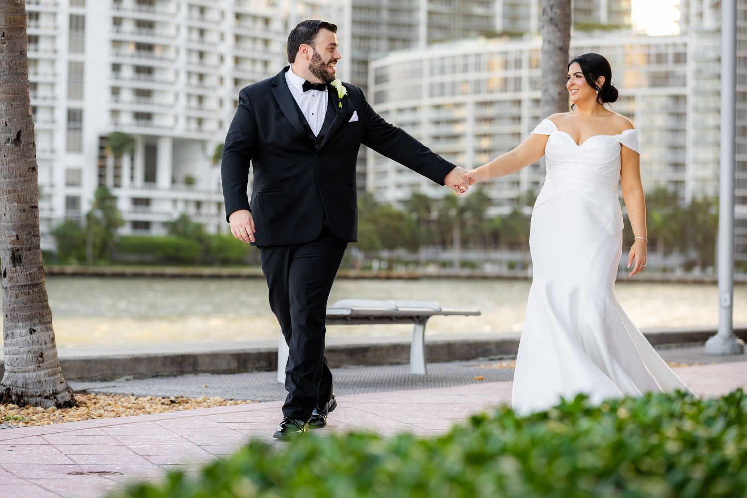 Wedding couple walking playfully along an outdoor pathway.