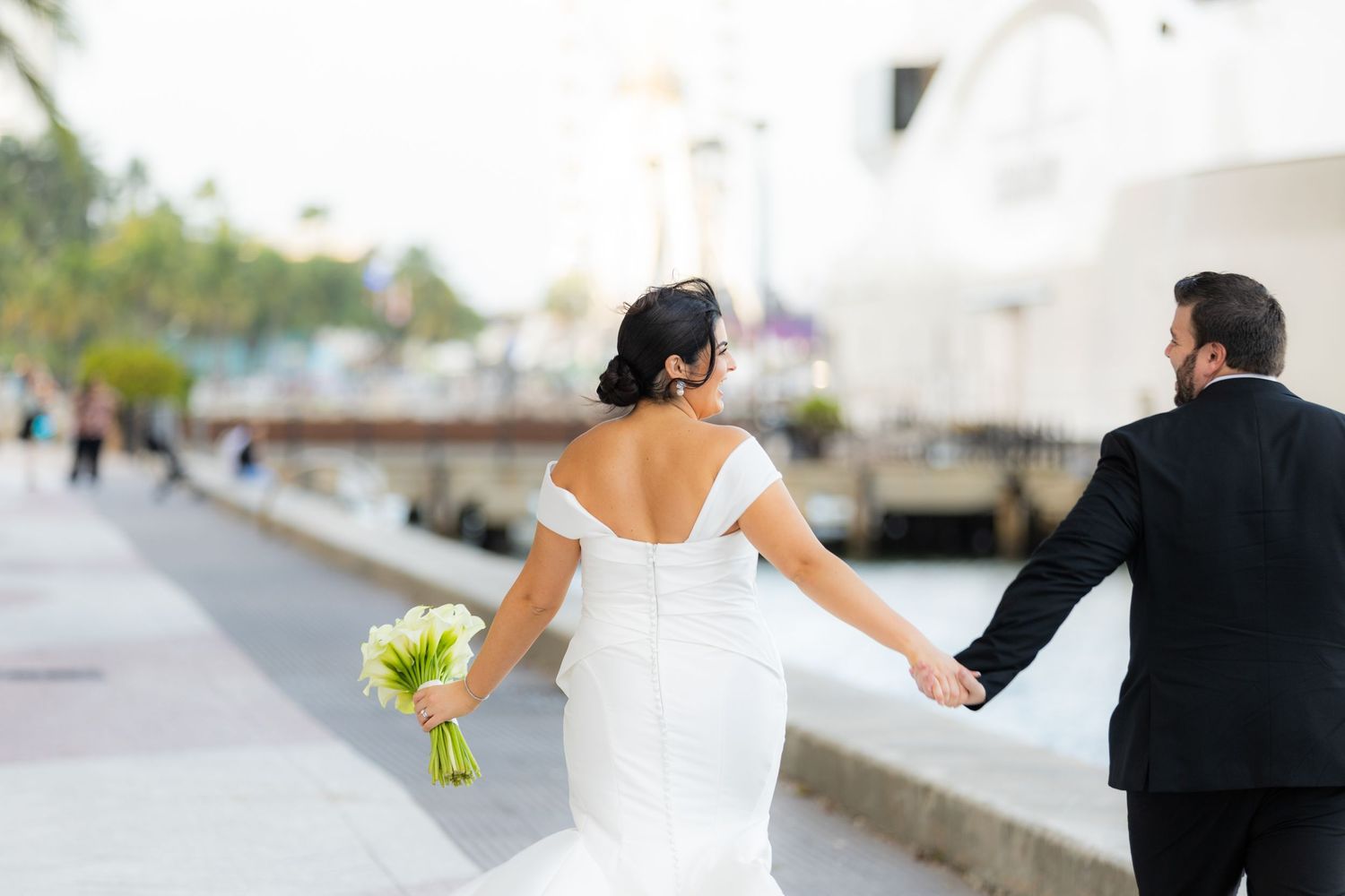 A couple in formal wedding attire walking together during a sunny outdoor photo session.