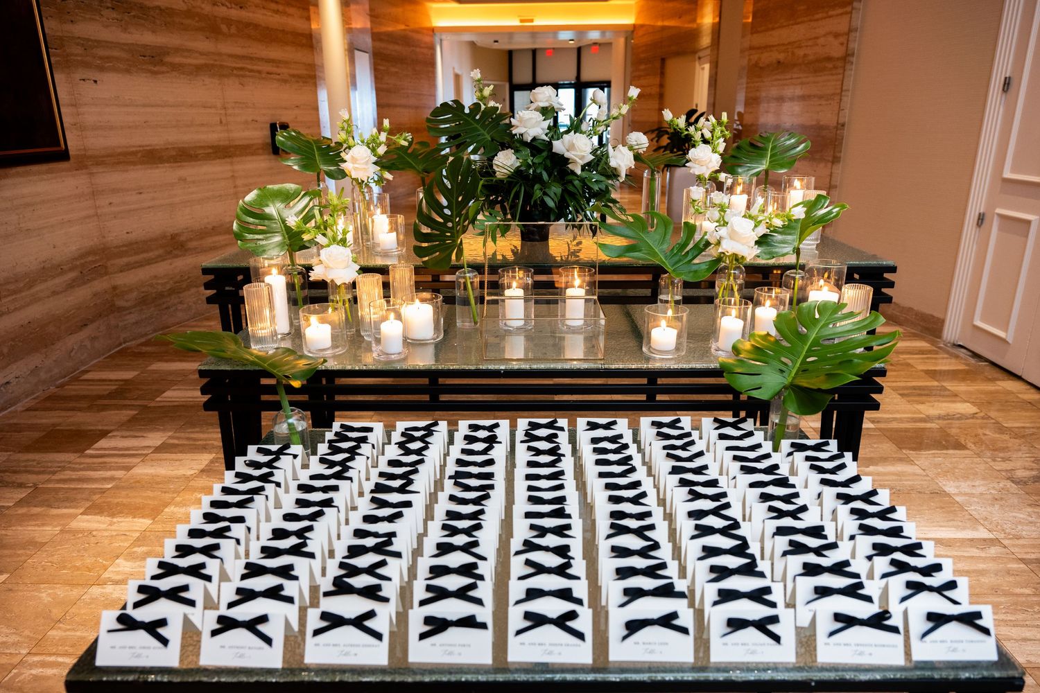 Wedding seating cards arranged in geometric patterns with greenery and candle decorations.