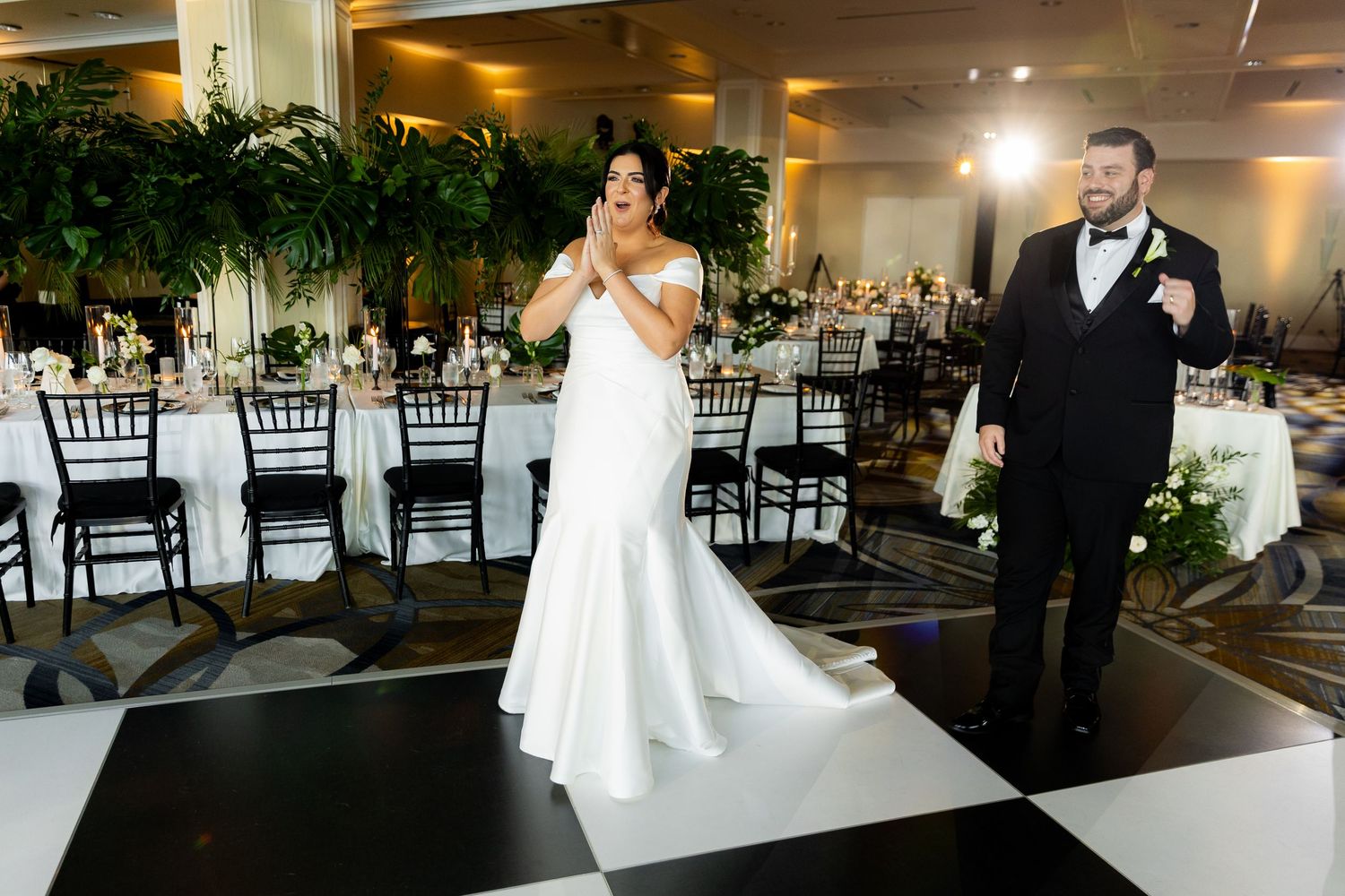 Elegant wedding reception setup with black chiavari chairs and white linens in a modern venue.