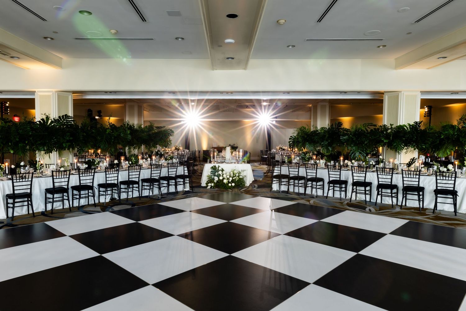 Large modern reception hall with black and white checkered dance floor and elegant table settings.