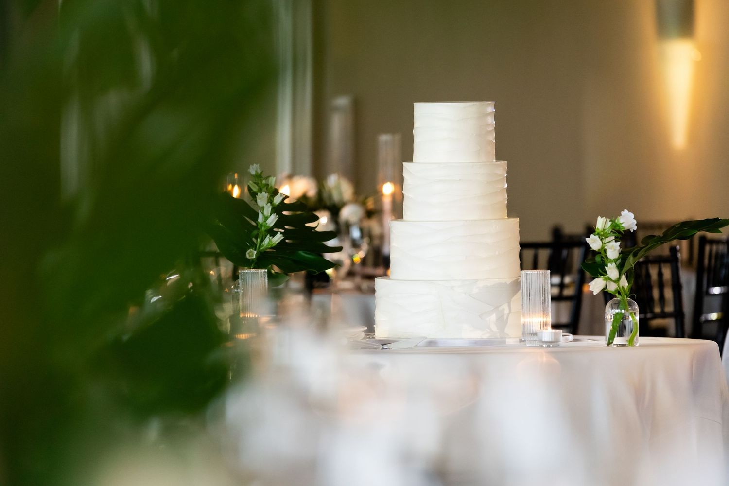 Elegant white wedding cake with floral decorations displayed at reception venue.