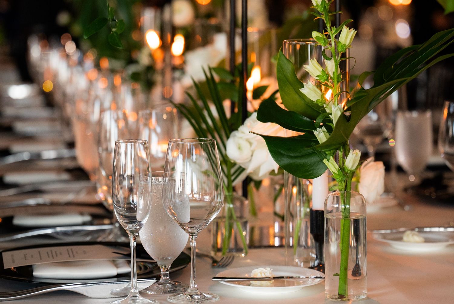 Elegant table setting with wine glasses and tropical floral centerpieces for wedding reception.